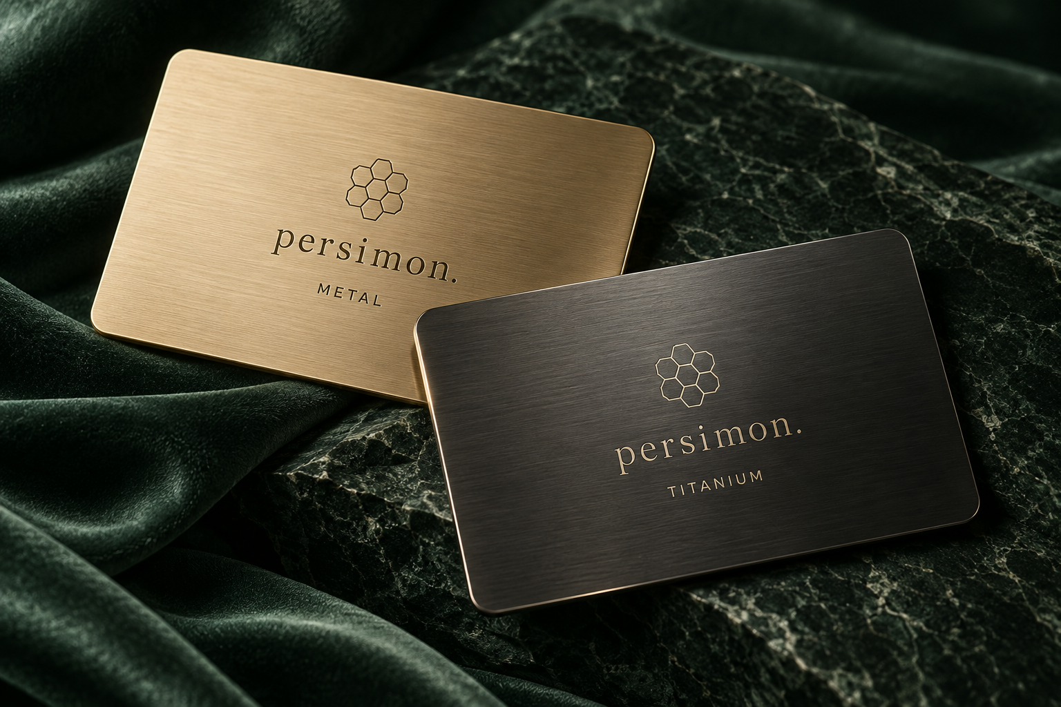 Two Persimon membership cards: brushed champagne metal and dark titanium on deep green fabric