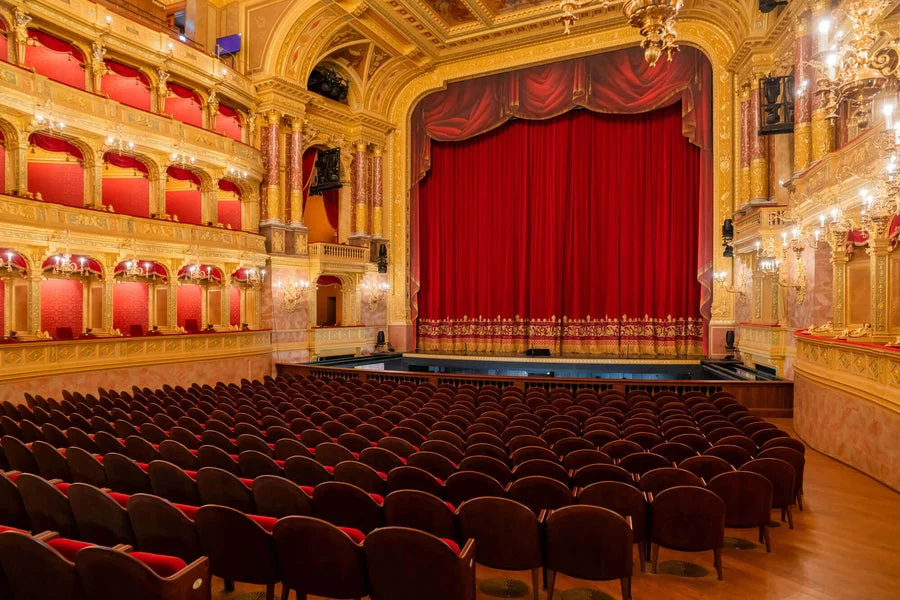 An ornate opera auditorium with gilded balconies and red velvet seating